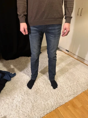 Mörkblå slim fit jeans herr - Säljer ett par mörkblå slim fit jeans med klassisk femficksdesign och snygg tvätt. Jeansen har smal passform och normal midja, perfekta till en avslappnad stil. Materialet är mjukt och stretchigt för extra komfort.