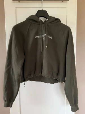 Olivgrön cropped hoodie Calvin Klein - Olivgrön cropped hoodie från Calvin Klein Jeans✨Stl. S. Köparen betalar frakt.