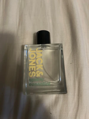 Jack & Jones Sparkly Essential parfym - Fräsch parfym från Jack & Jones i modellen Sparkly Essential. Flaskan är rektangulär i genomskinligt glas med svart kork och tydlig logga i gult och grönt. Perfekt för dig som gillar stilrena och moderna dofter.