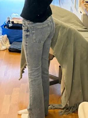 Ljusblå bootcut jeans från Gina Tricot petite - Säljer ett par ljusblå bootcut jeans med klassisk femficksdesign och hög midja. Jeansen har en snygg tvättad look och är tillverkade i denim med lite stretch för skön passform. Perfekta för dig som gillar en avslappnad och trendig stil.