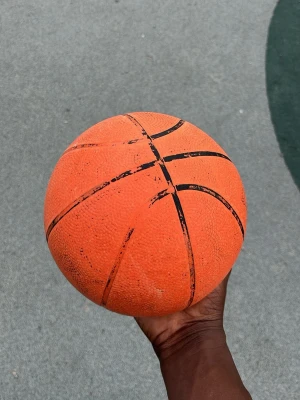 Orange basketboll med svarta linjer - En klassisk orange basketboll med svarta linjer. Bollen har en greppvänlig yta i gummi och är perfekt för spel på utomhusplaner. Ingen synlig logga eller märke. Passar för både träning och spontanspel med vänner.