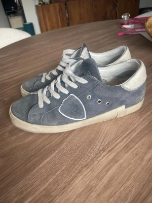 Bud/byter Philippe Model - Snygga sneakers i grå mocka från Philippe Model med vita detaljer och snörning. Skorna har en låg silhuett, vit sula och ikonisk sköld på sidan. Perfekta för dig som gillar en clean och avslappnad stil. De är storlek 38. Fint skick lite smutsiga men när man har på dem så syns det inte. Jag tar helst byten i storlek 37-39 eller lägg bud. Jag svarar inte på onödiga frågor som tex att jag säljer skorna för 1kr. Box följer med.