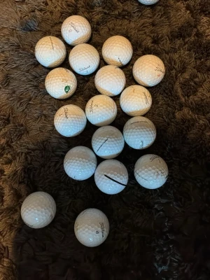 Vita Titleist golfbollar 18  - Ett gäng vita golfbollar från Titleist med klassisk dimple-design. Perfekta för dig som vill fylla på golfbagen med extra bollar. Några har svarta markeringar och logga. Säljes i blandad uppsättning.