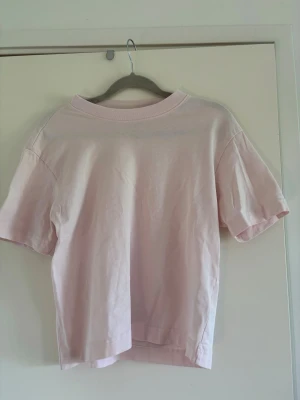 Ljusrosa t-shirt från Gina Tricot - Säljer en ljusrosa t-shirt från Gina Tricot, basics-kollektionen. T-shirten har en klassisk passform med korta ärmar och rund halsringning. Perfekt till alla dina outfits. Pytteliten fläck/sträck som man kan se på sista bilden, syns knappt