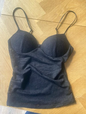 Svart spetslinnetopp med tunna band från Zara - Snygg svart linnetopp med tunna axelband och vadderade kupor. Toppens yta är täckt av fin spets som ger en elegant look. Perfekt att styla till olika outfits för en trendig vibe. Prislapp kvar!