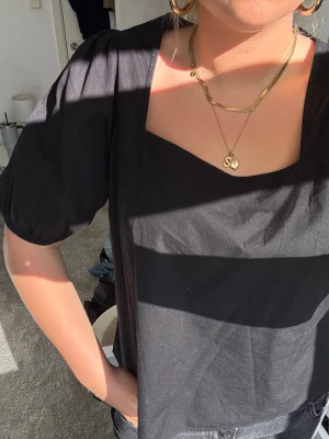 Svart blus med puffärmar - Svart blus med fyrkantig ringning och puffiga korta ärmar. Tillverkad i ett mjukt bomullstyg som känns skönt mot huden. Perfekt för dig som gillar en stilren och trendig look. Är i storlek L men passar S! 