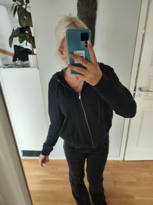 Mörk blå zip hoodie med huva - En mörkblå hoodie med dragkedja framtill och huva med dragsko. Hoodien har två fickor på magen och ribbade muddar vid ärmslut och nederkant. Tillverkad i mjukt bomullsmaterial, perfekt för en avslappnad look. Jag skulle säga att den ser bra ut och inte "använd ut".