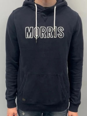 Morris hoodie - Färg: Mörkblå/svart med vit “MORRIS”-logga på bröstet Storlek: L  Skick: Använd några gånger, inget slitage eller defekter. Bra skick.  Snygg och avslappnad hoodie från Morris med tydlig logga och bekväm passform. Perfekt för vardag, både till jeans och joggers. 