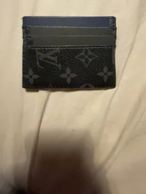 En svart solon bok öppen för byten. Pris kan diskuteras  - Snyggt svart kortfodral från med klassiskt monogrammönster i grått. Fodralet har flera kortfack och är tillverkat i tåligt lädermaterial. Perfekt för dig som vill ha en stilren och lyxig accessoar i fickan.