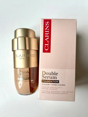Clarins Double Serum Foundation L3W - Otroligt populära Clarins Double Serum Foundation i nyansen L3W. Nypris 695 kr och inhandlad på Kicks. Testad en gång men råkade köpa en för mörk nyans. En nästa generations hybrid-serumfoundation vars banbrytande fusion av makeup och hudvård erbjuder en ny nivå av ungdomlig lyster. Tack vare sin justerbara ratt ger den viktlös, anpassningsbar medium-till-full täckning med en strålande, satinliknande, icke-oljig finish i 37 nyanser för alla hudtyper och hudtoner.
