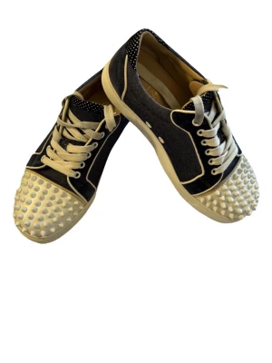 Christian Louboutin sneakers med nitar - Unika sneakers från Christian Louboutin i mörkblå denim med vita detaljer och vita snören. Tåpartiet är täckt av coola vita nitar och insidan är i beige läder. Snygg kontrast mellan material och färger, perfekt för dig som vill sticka ut. Har inget kvitto men köpa från vestiarie och gått igenom äktahets bevis kontrollen, så garanterat äkta. Kommer med en påse. Kan tänka sänkas pris vid snabb affär 