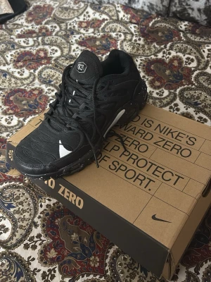Nike Air Max Plus svarta sneakers - Säljer ett par svarta Nike Air Max Plus sneakers med vita detaljer och synlig Air Max-sula. Skorna har en sportig design med mesh och syntetmaterial, samt den klassiska Swoosh-loggan på sidan. Perfekta för dig som gillar streetwear och vill ha något stilrent.