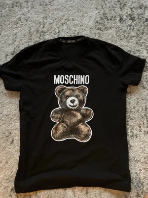 En moschino T-shirt - En T-shirt från moschino som är i väldigt bra skick. Den är i storlek M. Hör av dig vid frågor.