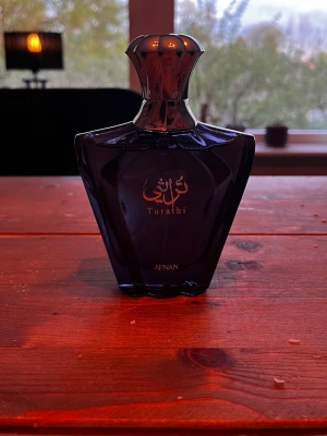 Afnan Turathi parfymflaska - En elegant och fräsch herrparfym med uppfriskande citrusnoter i öppningen, följt av varma tränoter och amber. Basen av mysk, patchouli och kryddor ger en maskulin och långvarig doft som passar både till vardags och fest. En modern, sofistikerad parfym med premiumkänsla 