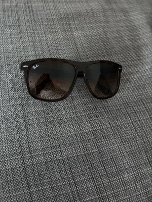  Ray-Ban Boyfriend 4147 solglasögon - Trendiga laminerade Boyfriend solglasögon från Ray-Ban med gradient glas och stilren design. Bågarna är i plast och har en tidlös form som passar de flesta ansikten. Perfekta för att ge din look en cool touch. Storlek 60