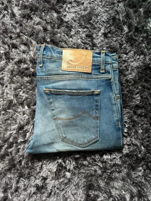 Jacob Cohen jeans - Ljusblå jeans från Jacob Cohen med lagade slitningar. Storlek 31/31 men sitter som 32/32 midja 43cm ytterbenlängd 101cm. 