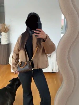 Beige bomberjacka med dragkedja - Säljer en beige bomberjacka i syntetmaterial med klassisk krage och dragkedja framtill. Jackan har en loose passform och två fickor på sidorna. Perfekt för dig som gillar en avslappnad och trendig stil. Köpt från Zara kids den e alltså 12-14 men motsvarar xs