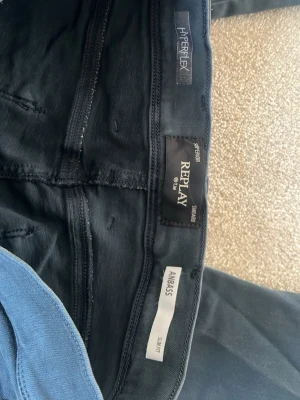 Mörkblå Replay Hyperflex jeans - Snygga mörkblå jeans från Replay i modellen Anbass med slim fit-passform. Jeansen är tillverkade i Hyperflex-material som ger extra stretch och komfort. Klassisk femficksdesign och diskreta detaljer på bakfickorna.