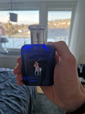 Ralph Lauren Polo Blue parfym - Snygg parfymflaska från Ralph Lauren i djupblått glas med silverfärgat lock och klassisk Polo-logga framtill. Flaskan har en stilren och modern design som passar perfekt på hyllan. Perfekt för dig som gillar fräscha och sportiga dofter.