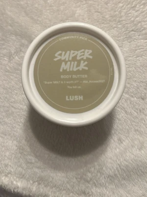 Lush Super Milk Body Butter - Super Milk Body Butter från Lush i en rund vit plastburk med beige etikett. Perfekt för att återfukta huden och ge en mjuk känsla. Smidig att ta med i väskan och enkel att applicera. Doftar fräscht och passar alla hudtyper. 