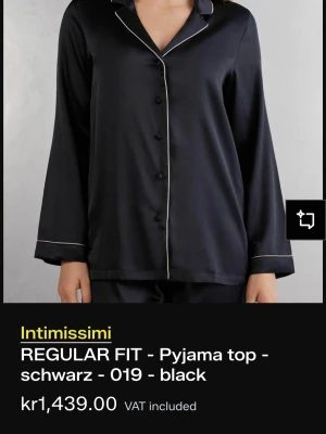 Svart pyjamaströja från Intimissimi - Stilren svart pyjamaströja från Intimissimi i regular fit med klassisk krage och knäppning framtill. Tröjan har kontrasterande vita passpoaler längs krage och ärmslut för en elegant touch. Perfekt för mysiga kvällar hemma.