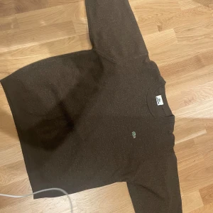 Brun stickad Lacoste tröja - Snygg tröja från Lacoste i bra skick. Pris kan diskuteras.