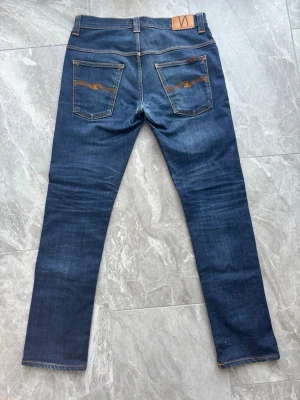 Nudie Jeans - Ett par fetta nudie jeans i modellen tape Ted vilket är en liknande modell av lean dean. Storlek W32 L32. En liten defekt som inte märks mellan benen som är lagat. De är inget märkvärdigt.Frägen är 16 dips dry vilken ett riktigt snyggt. Skriv vid funderingar!😁
