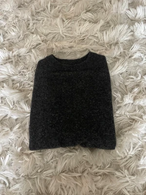Mörkgrå stickad tröja - En enkel och stilren mörkgrå stickad tröja med rund halsringning. Tröjan har en klassisk passform och är gjord i ett mjukt, värmande material som passar perfekt för kyligare dagar. Storlek 170 men sitter som en xs-s