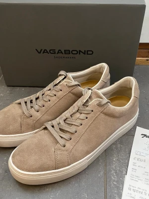 Beige sneakers från Vagabond (Oanvända) - Snygga beige sneakers från Vagabond med klassisk låg profil och stilren design. Skorna är tillverkade i mocka med matchande beige snörning och vit sula. Perfekta för dig som gillar en clean och modern look. Storlek 42 men passar mer som 43. Snabb Leverans!