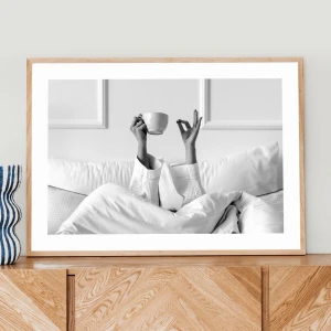 Svartvit poster - kaffe i sängen 50x40 - Stilren svartvit poster som visar en person i sängen med armarna upp, hållandes en kaffekopp. Perfekt som modern väggkonst till sovrum eller vardagsrum. 50x40cm, ram ingår ej