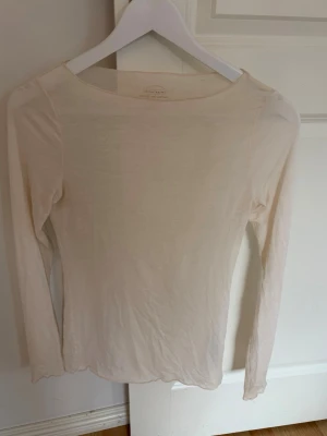 Ljusbeige långärmad topp Intimissimi - Superskön och tunn långärmad topp från Intimissimi i en ljusbeige färg. Tillverkad i en mjuk blandning med kashmir som känns lyxig mot huden. Enkel, stilren design med rund halsringning och smal passform.