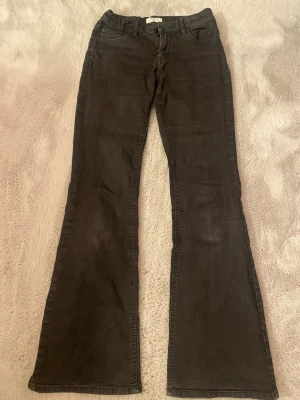 Svarta bootcut jeans från Lindex - Säljer ett par svarta bootcut jeans från Lindex, utsvängda ben och normal midja. Perfekta för dig som gillar en retroinspirerad look med bekväm passform. Materialet är mjukt denim med lite stretch.