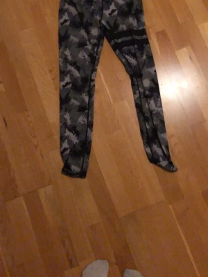 Camo-mönstrade träningsleggings - Snygga träningsleggings med grått och svart camo-mönster. Tight passform och stretchigt material som passar perfekt till gymmet eller löprundan. Hög midja för extra komfort och stöd.