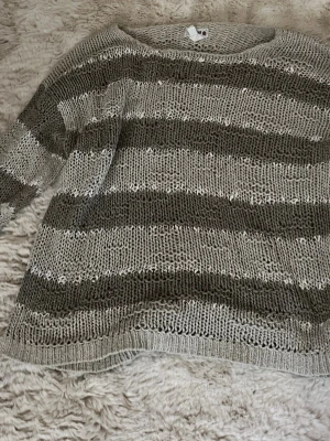 Randig stickad tröja i beige och grå - Stickad tröja med breda horisontella ränder i beige och grå toner. Tröjan har rund halsringning och avslappnad passform.❣️