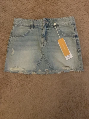 Jeans kjol - En fin ljus blå jeanskjol med rosa detaljer på bakfickorna från Gina Tricot Young i storleken 164