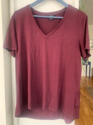 Vinröd v-ringad t-shirt från Amisu - Säljer en enkel och snygg vinröd t-shirt från Amisu. T-shirten har v-ringning, korta ärmar och normal passform. Tillverkad i mjuk bomull som känns skön mot huden. Perfekt till jeans eller kjol för en avslappnad look.