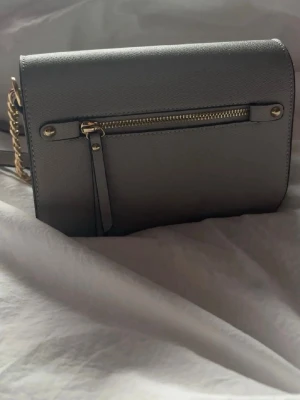 Grå väska - Grå väska som är köpt på en marknad med axelremsband! Har två fläckar på sig, se bilder