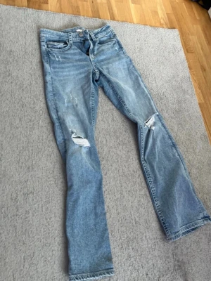Ljusblå slitna jeans med raka ben - Ljusblå utsvängda jeans.med hål på knäna