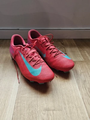 Nike Mercurial rosa fotbollsskor - Säljer ett par Nike Mercurial fotbollsskor i en snygg rosa färg med turkosa detaljer och Nike-logga. Använda ett fåtal gånger. 