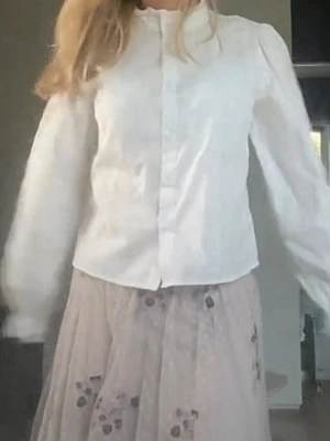 Vit blus - Stilren vit blus med lite puffiga långärmar och knäppning framtill. Klassisk rak passform och rund halsringning. Perfekt att matcha med kjol eller jeans för en trendig look.