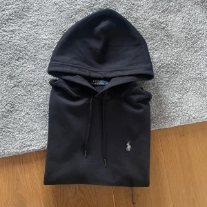 Svart hoodie från Polo Ralph Lauren - Hej! Säljer en svart Ralph lauren hoodie i storlek S. Hoodien är i mycket bra skick. Har en minimal slitning men syns inte vid användning