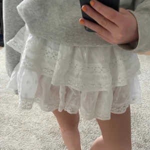 Vit volangkjol med spetsdetaljer - Supersöt vit kortkjol med flera lager volanger och fina spetsdetaljer. Så fin kjol från american eagle. Köpt i usa för nått år sedan så går inte att få tag på, köpt för 800