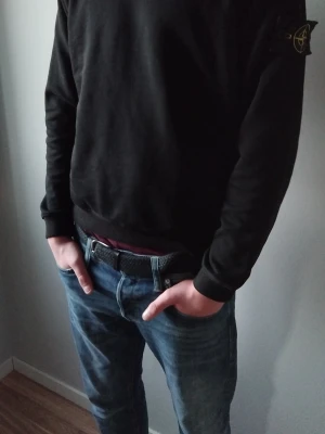 Svart sweatshirt med batch - Säljer en svart sweatshirt med den klassiska logotypen på vänster ärm. Tröjan har rund hals, ribbade muddar och en avslappnad passform. Perfekt för dig som gillar streetwear och enkel stil.