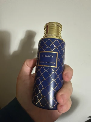 Maison Asrar Legacy (ex nihilo blue talisman) - Snygg parfymflaska från Legacy Royal Collection med mörkblått och guldigt mönster. Flaskan har en lyxig känsla med guldfärgat lock och detaljer. Perfekt för dig som gillar exklusiva dofter och elegant design. 90% kvar, OBS! Saknar original förpackning!