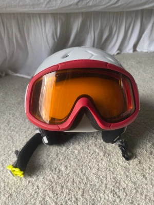 Röda skidglasögon  - Säljer ett par röda skidglasögon med orange tonade linser. glasögonen har elastiskt band med röda detaljer. Perfekt för vintersport bredd ca 18 cm 