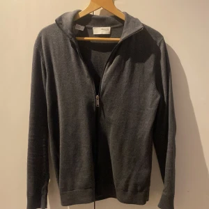 Mörkgrå full zip med dragkedja från Selected Homme - Säljer en stilren mörkgrå tröja från Selected Homme. Tröjan har en praktisk dragkedja framtill och långa ärmar. Perfekt för en avslappnad och snygg look.          