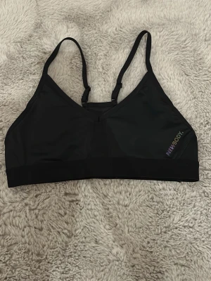 Svart sport-bh från Newbody - Säljer en svart sport-bh från Newbody med tunna, justerbara axelband och diskret logga på sidan. Bh:n är tillverkad i ett stretchigt och mjukt material som passar perfekt för träning och aktivitet. Finns uttagbara kuddar i. Aldrig använd, endast testad, köpt för 200+ för ca 2 månader sedan. 