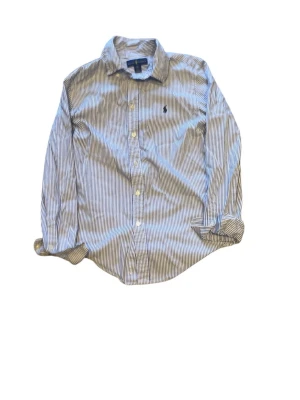 Randig skjorta från Ralph Lauren - Klassisk skjorta från Ralph Lauren med blå och vita ränder. Skjortan har lång ärm, knappar framtill och broderad logga på bröstet. Tillverkad i bomull och har en tidlös krage. Perfekt för en stilren look.