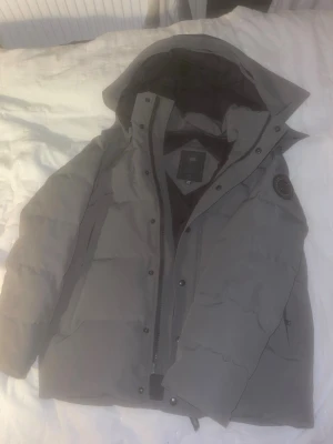 Grå Canada Goose Black Label Puffer Jacka - Helt äkta Canada Goose black Label jacka. Storlek medium. Inköpspriset är 16000kr. Finns bevis på äktahet och ni kan även kolla på plats när vi möts. Har använts ett väldigt fåtal gånger och är i princip som ny. Helt ren inga fläckar eller inget slitage någonstans. 