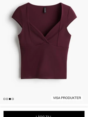 Vinröd v-ringad tröja från H&M - Helt ny♥️Vinröd topp från HM med omlottdesign och v-ringning. Modellen är croppad med korta ärmar och har en figurnära passform. Perfekt att styla med jeans eller kjol för en trendig look.